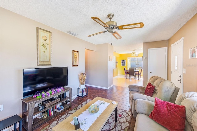 living room featuring ceiling fan, wood-type flooring, and a textured ceiling