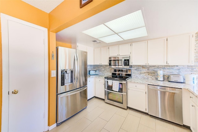 kitchen featuring stainless steel appliances, white cabinets, and decorative backsplash