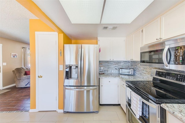 kitchen with white cabinetry, light stone countertops, tasteful backsplash, and stainless steel appliances