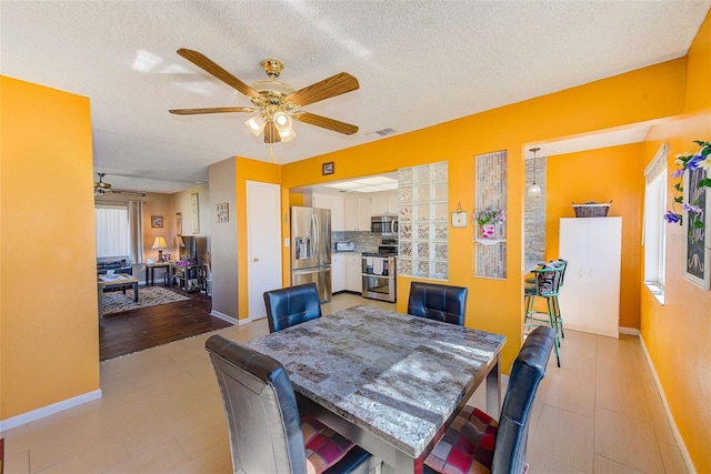 dining space featuring ceiling fan and a textured ceiling