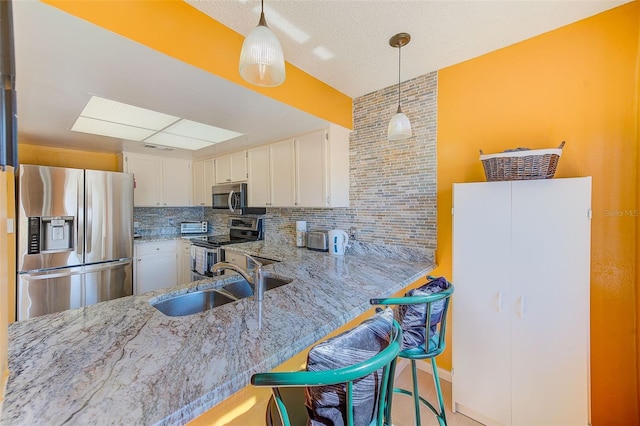 kitchen with sink, a kitchen breakfast bar, kitchen peninsula, stainless steel appliances, and white cabinets