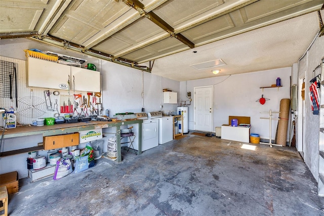 garage with independent washer and dryer, electric water heater, and a workshop area