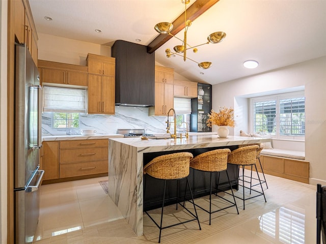 kitchen featuring a breakfast bar area, sink, high quality fridge, and a center island with sink