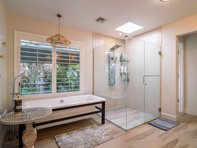 bathroom featuring hardwood / wood-style flooring, a skylight, and plus walk in shower