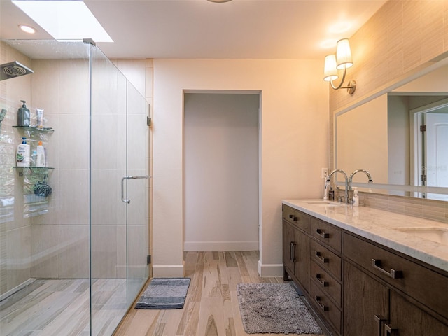 bathroom with hardwood / wood-style flooring, vanity, a skylight, and walk in shower