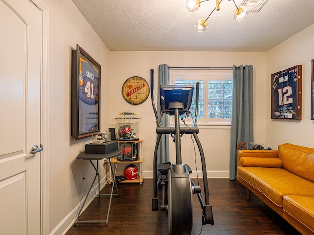 exercise room with dark wood-type flooring and a textured ceiling