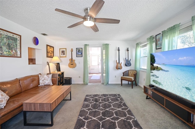 carpeted living room featuring ceiling fan and a textured ceiling