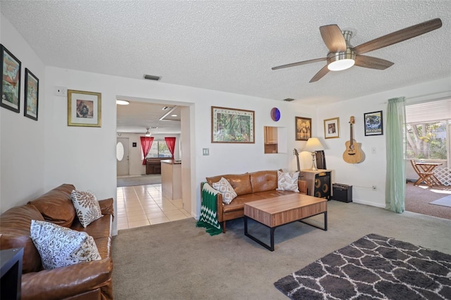 carpeted living room featuring ceiling fan and a textured ceiling