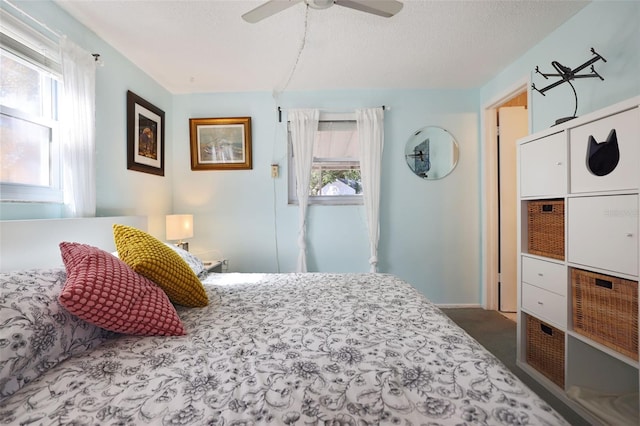 carpeted bedroom featuring ceiling fan, multiple windows, and a textured ceiling