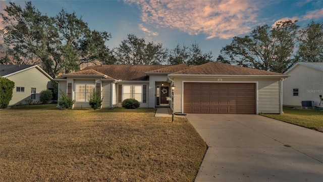 single story home featuring a garage, a lawn, and central air condition unit