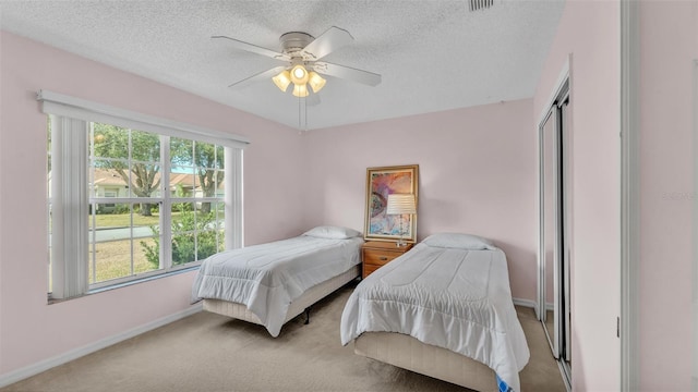bedroom with baseboards, carpet floors, a textured ceiling, a closet, and ceiling fan