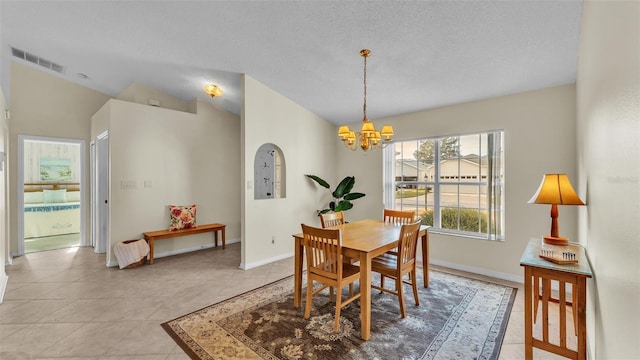 dining room featuring a chandelier, light tile patterned flooring, baseboards, lofted ceiling, and a textured ceiling