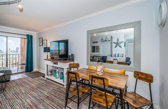 dining space with crown molding and track lighting