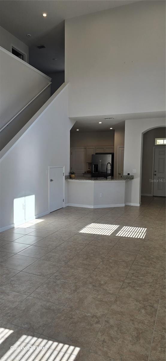 unfurnished living room featuring a high ceiling and light tile patterned floors