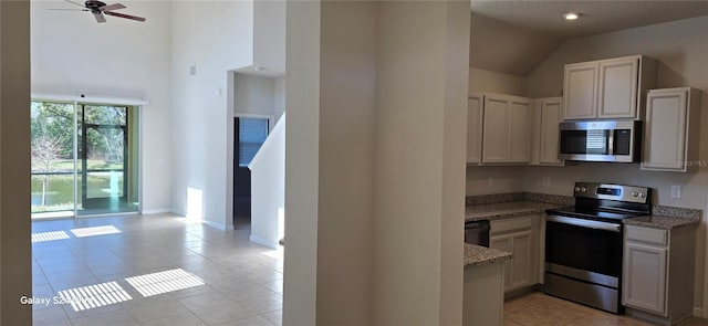 kitchen featuring light tile patterned flooring, high vaulted ceiling, appliances with stainless steel finishes, stone counters, and ceiling fan