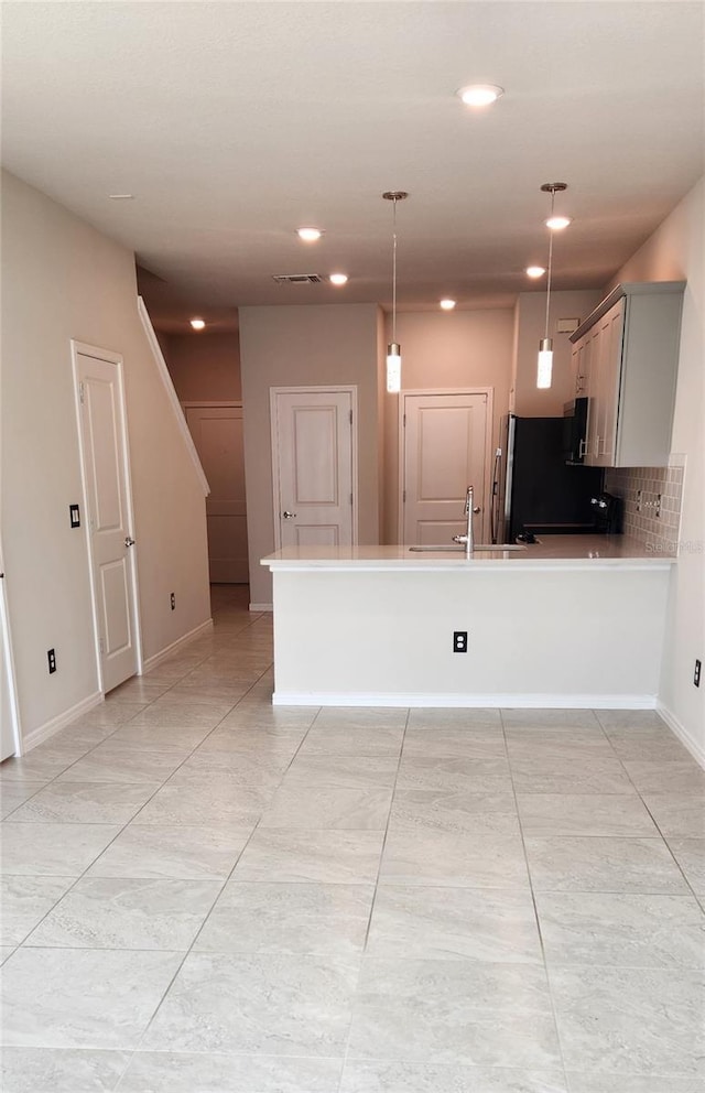 kitchen featuring sink, refrigerator, kitchen peninsula, pendant lighting, and decorative backsplash