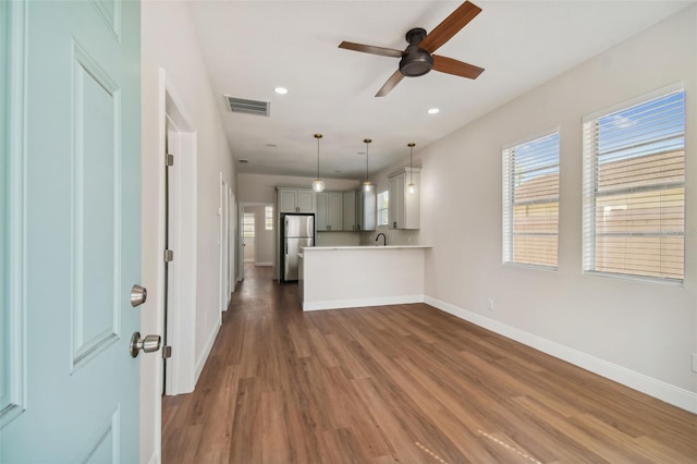 unfurnished living room with sink, dark hardwood / wood-style floors, and ceiling fan