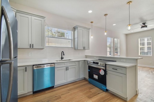 kitchen with pendant lighting, sink, kitchen peninsula, and appliances with stainless steel finishes