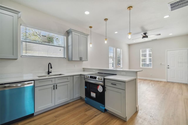 kitchen with pendant lighting, sink, kitchen peninsula, stainless steel appliances, and light wood-type flooring