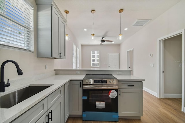 kitchen featuring sink, gray cabinets, electric range, light stone counters, and decorative light fixtures