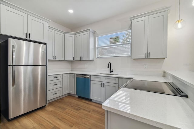 kitchen with sink, decorative light fixtures, light wood-type flooring, appliances with stainless steel finishes, and gray cabinets