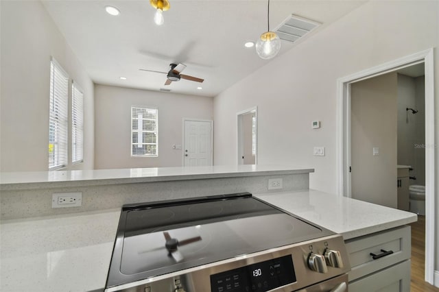 kitchen with light stone counters, stainless steel electric range oven, gray cabinets, pendant lighting, and ceiling fan