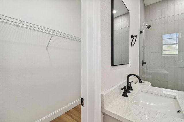 bathroom with vanity, tiled shower, and hardwood / wood-style floors