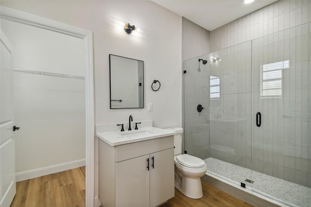 bathroom featuring hardwood / wood-style flooring, vanity, toilet, and a shower with shower door