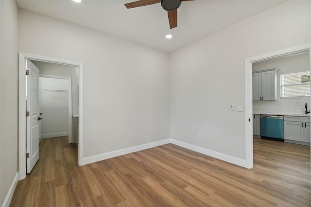 unfurnished bedroom featuring ceiling fan, sink, a spacious closet, and light hardwood / wood-style floors