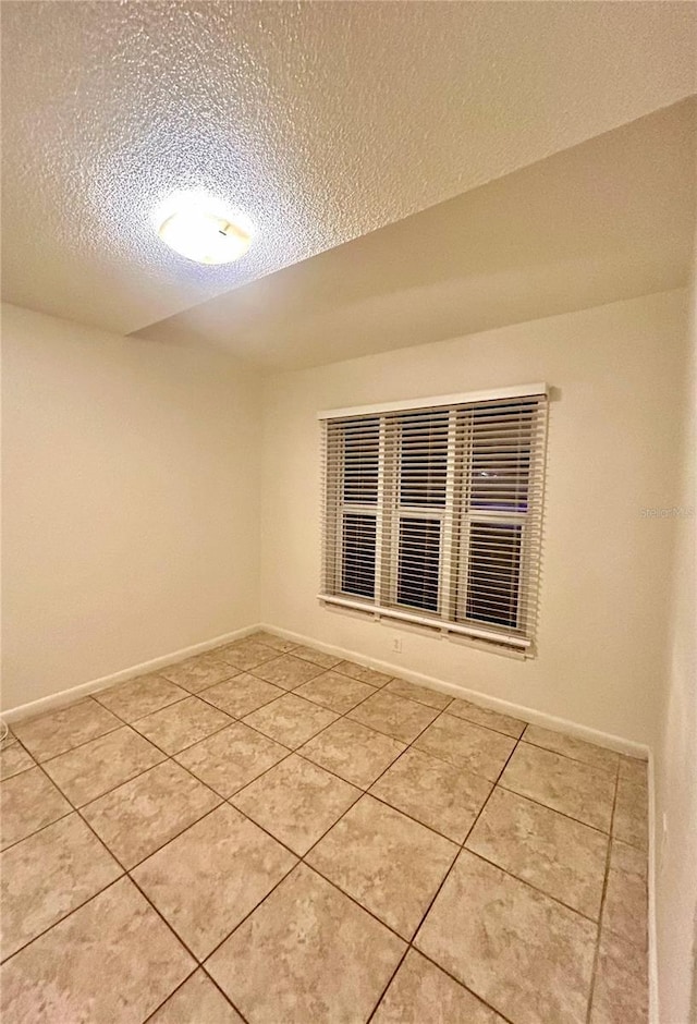 tiled empty room featuring a textured ceiling