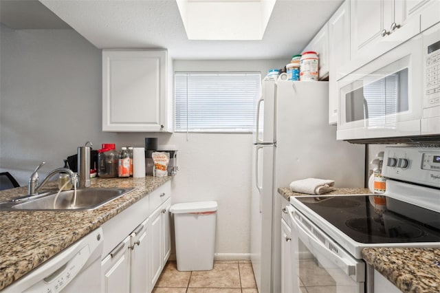 kitchen with white cabinetry, sink, white appliances, and dark stone counters