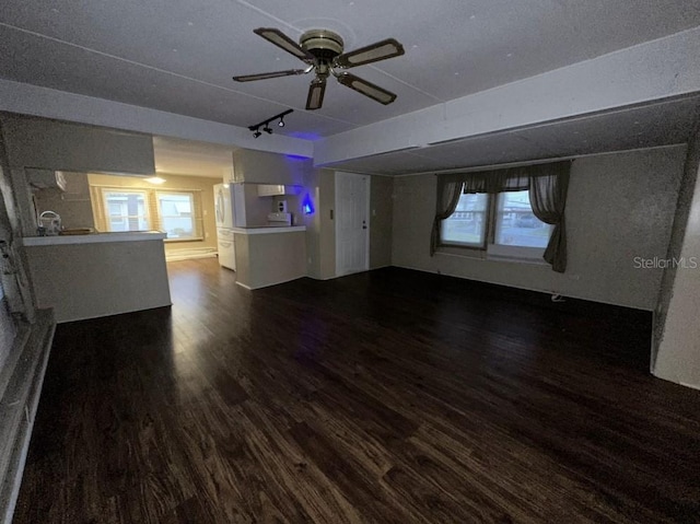 unfurnished living room with ceiling fan, track lighting, and dark hardwood / wood-style flooring