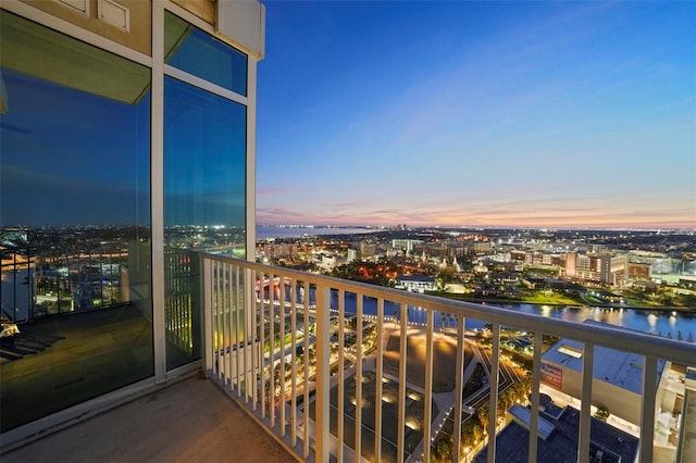 balcony at dusk featuring a water view