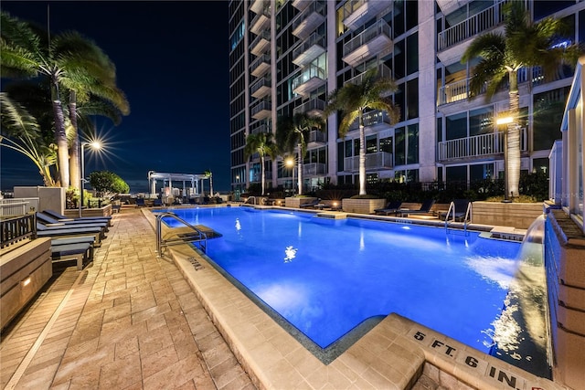 pool at twilight featuring a patio area