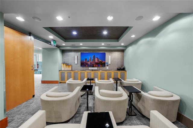 cinema with carpet flooring, a barn door, and a raised ceiling