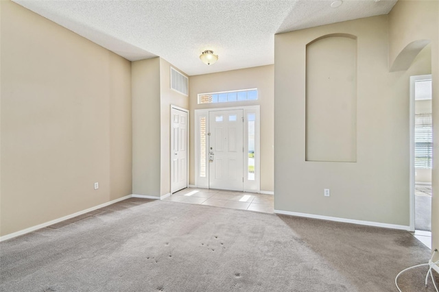 carpeted entryway with a healthy amount of sunlight, a textured ceiling, and a high ceiling