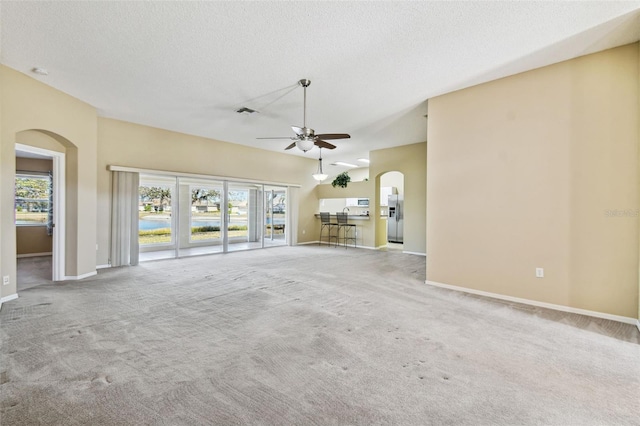 unfurnished living room featuring a textured ceiling, light colored carpet, and ceiling fan