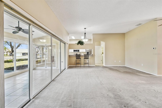 unfurnished living room with ceiling fan, light carpet, and a textured ceiling