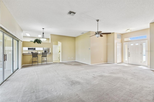 unfurnished living room with ceiling fan, light colored carpet, and a textured ceiling