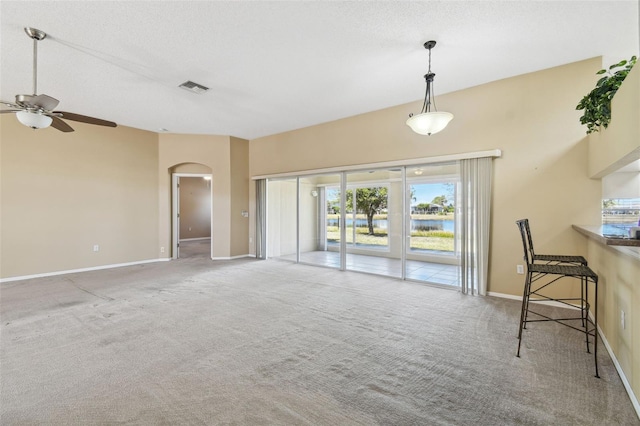 unfurnished living room with ceiling fan, light colored carpet, and a textured ceiling