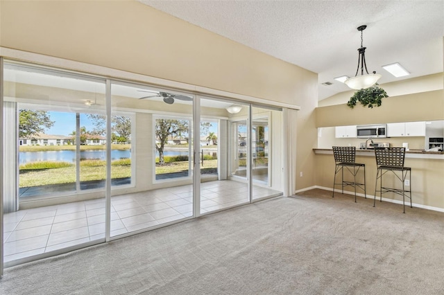 unfurnished living room featuring a water view, light carpet, lofted ceiling, and a textured ceiling