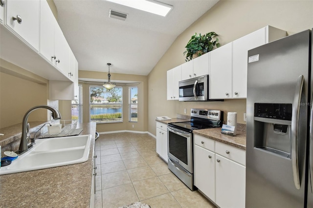 kitchen featuring sink, white cabinetry, stainless steel appliances, light tile patterned flooring, and decorative light fixtures