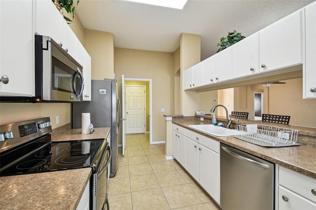 kitchen featuring stainless steel appliances, light tile patterned flooring, sink, and white cabinets