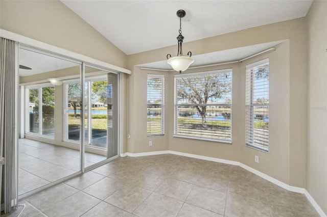 unfurnished dining area with lofted ceiling, light tile patterned floors, and plenty of natural light