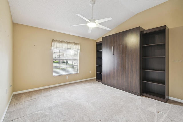 unfurnished bedroom featuring ceiling fan, a textured ceiling, vaulted ceiling, light colored carpet, and a closet