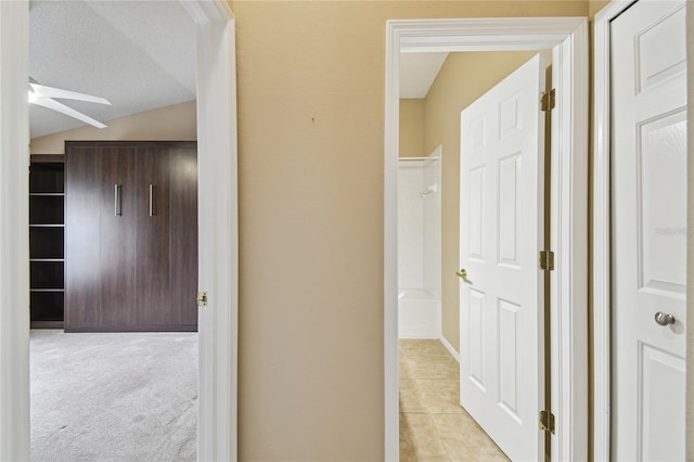 hallway with light colored carpet and vaulted ceiling