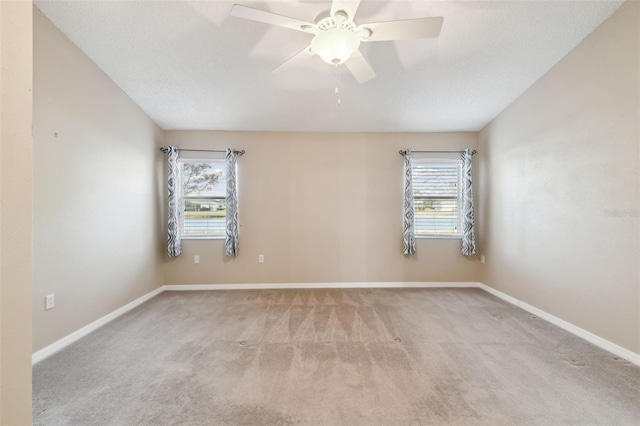 carpeted spare room with a textured ceiling, plenty of natural light, and ceiling fan