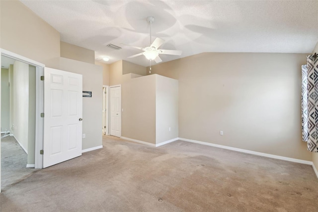 unfurnished room featuring ceiling fan, vaulted ceiling, a textured ceiling, and carpet