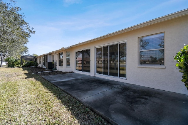 back of property with cooling unit, a yard, and a patio