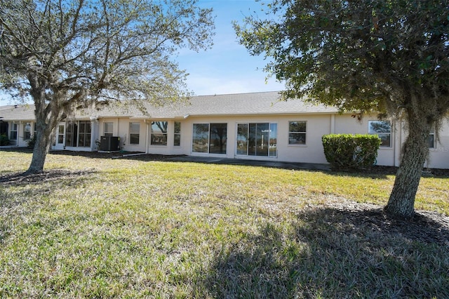 rear view of property with central AC unit and a lawn